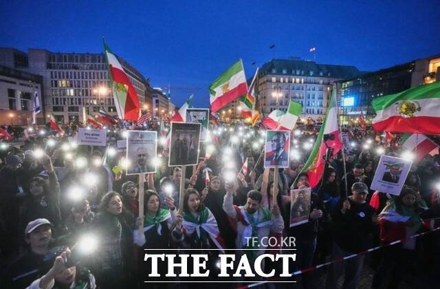 지난달 28일(현지시간) 독일 베를린 주재 미국 대사관 앞에서 열린 미국과 이스라엘의 이란 공습 지지 집회 참석자들이 미국에 망명 중인 레자 팔레비 왕세자 사진을 들고 있다. /베를린=AP.뉴시스