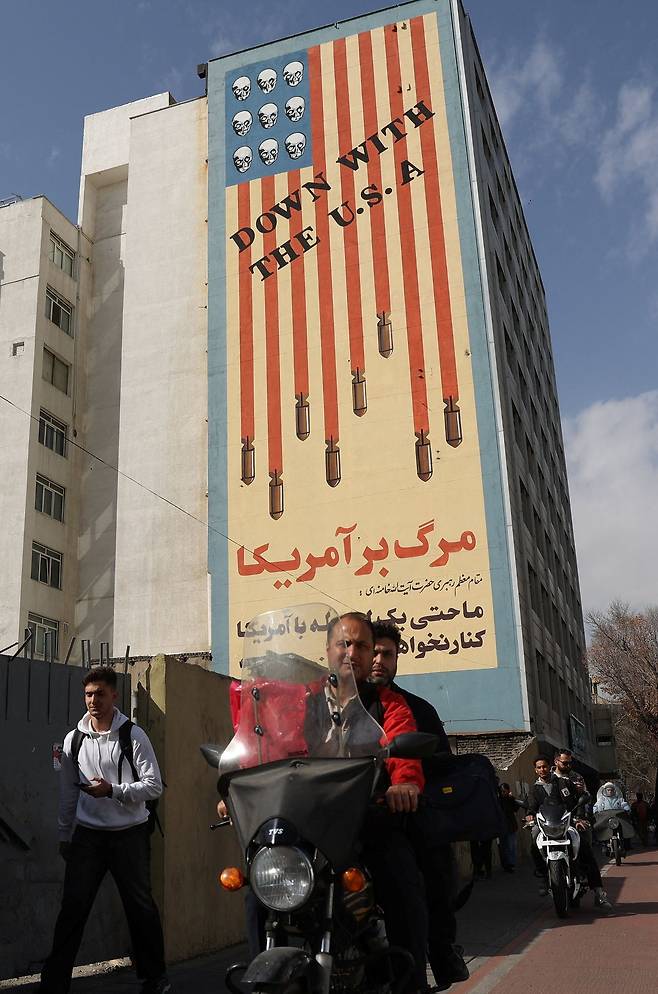 28일(현지시간) 이란 수도 테헤란 시내 건물 외벽에 “미국과 함께 격추돼라”라는 문구와 함께 미사일·해골 등이 그려진 반미 선전 벽보가 그려져 있다. EPA =연합뉴스