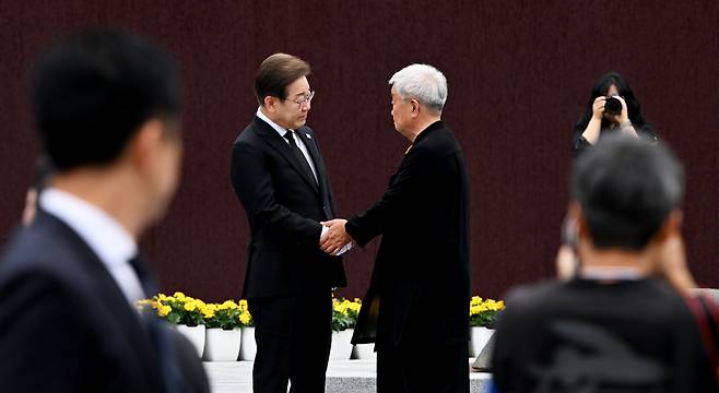President Lee Jae Myung, left, and actor Myung Kae-nam shake hands during a memorial ceremony for former President Roh Moo-hyun at Bongha Village in South Gyeongsang on May 23, 2025. [JOONGANG ILBO]