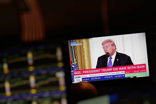 미국 뉴욕증권거래소(NYSE) TV에 2일(현지시간) 도널드 트럼프 대통령의 기자회견이 방송되고 있다. 이날 뉴욕 증시는 이란 전쟁 충격에도 불구하고 '패닉' 없이 기술주들이 상승세를 탔다. AP 뉴시스