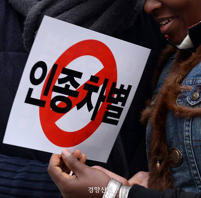 2016년 3월 13일 서울 보신각앞에서 열린 ‘인종차별 철폐의 날’ 행사에 참석한 한 이주노동자가 ‘인종차별 금지’라고 적힌 손팻말을 들고 자리에 앉아 있다. 그해 3월 21일은  UN이 제정한 ‘인종차별 철폐의 날’ 50주년이다. 서성일 기자