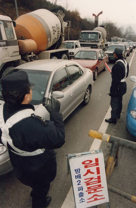 Police officers inspect vehicles to catch fugitive Shin Chang-won on a road connecting Gyeonggi and southern Seoul in January 1998. [JOONGANG ILBO]