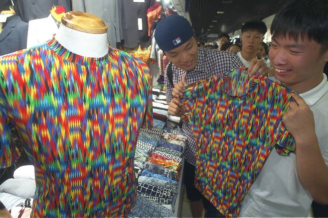 Two young men hold a T-shirt in a same design that fugitive Shin Chang-won wore during his arrest in July 1999. [JOONGANG ILBO]