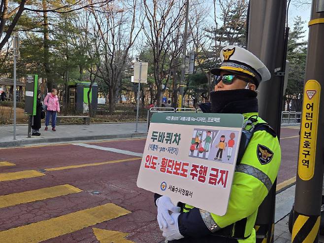 4일 오전 서울 수서경찰서 소속 교통경찰관이 '두바퀴차 인도횡단보도 주행 금지' 문구가 적힌 손팻말을 들고 계도에 나선 모습.(사진=김현재 기자)