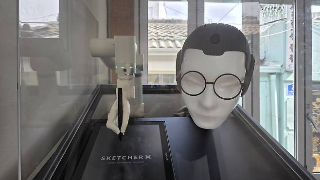 An AI robot named Dangun draws a caricature using a robotic arm at a cafe in Ikseon-dong in Jongno District, central Seoul [KIM CHANG-YONG]