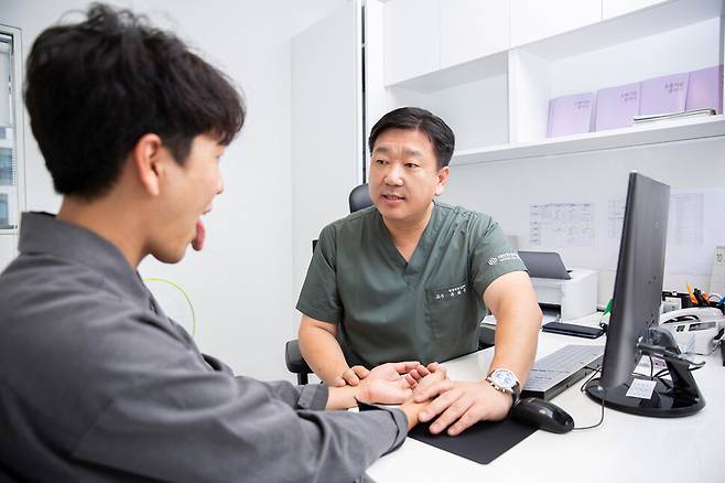 유화승 대전대 대전한방병원 교수가 환자의 맥을 짚으며 혀를 들여다보고 있다. 대전한방병원 제공