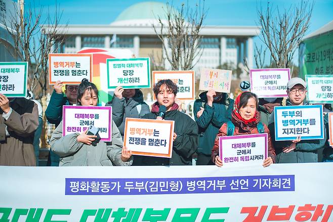 지난 2월 23일 서울 여의도 국회 앞에서 열린 병역거부 선언 기자회견에서 ‘두부’(활동명·김민형씨)가 “병역거부는 전쟁을 멈춘다”라고 적힌 손팻말을 들고 발언하고 있다. 전쟁없는세상 제공