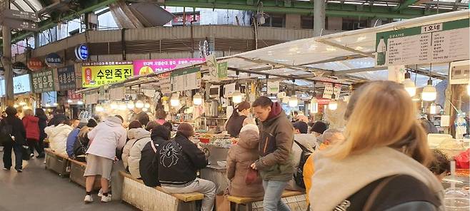 지난 6일 오후 서울 종로구 광장시장에서 외국인 관광객들이 먹거리 노점 앞에 줄지어 앉아 식사를 하고 있다. 사진=최승한 기자