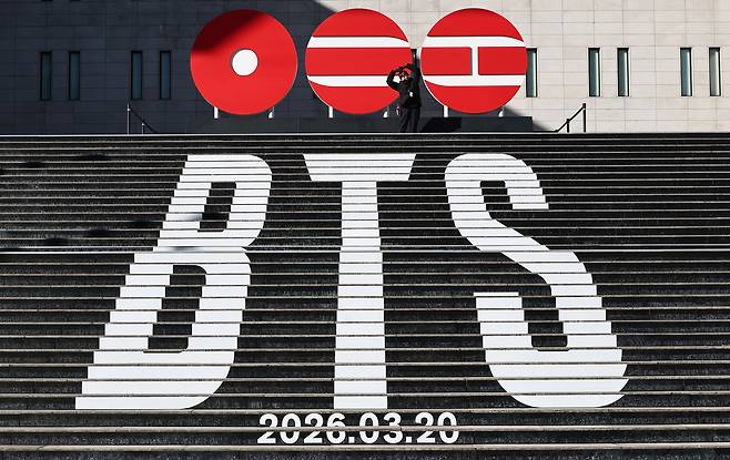 A fan poses on the stairs of the Sejong Center for the Performing Arts in central Seoul on Jan. 22, where a sculptural installation of BTS’ new album logo is on display. (Yonhap)