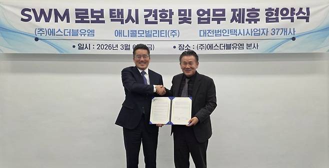 김기혁 SWM 대표(왼쪽)가 김성태 애니콜모빌리티 회장과 협약을 체결한 뒤 악수를 하고 있다. SWM 제공