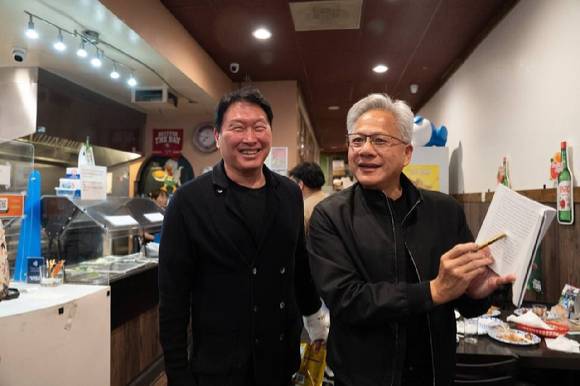 지난달 5일(현지시간) 미국 캘리포니아 산타클라라의 한국식 호프집 '99치킨'에서 가진 최태원 SK그룹 회장과의 만찬회동에서 젠슨 황 엔비디아 최고경영자가 신간 '슈퍼모멘텀'을 펼쳐보이고 있다. 2026.2.11 [사진=연합뉴스]