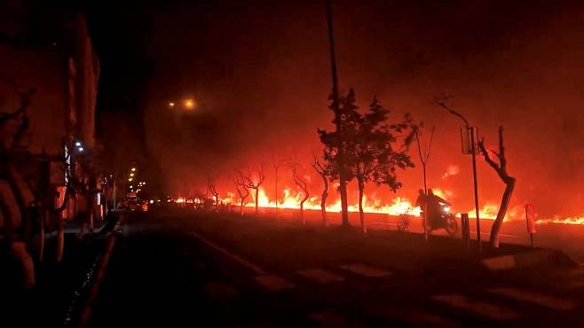 지난 8일 이란 테헤란의 쿠흐사르 대로에서 오토바이가 불타는 도로를 지나가고 있다. 로이터=연합뉴스