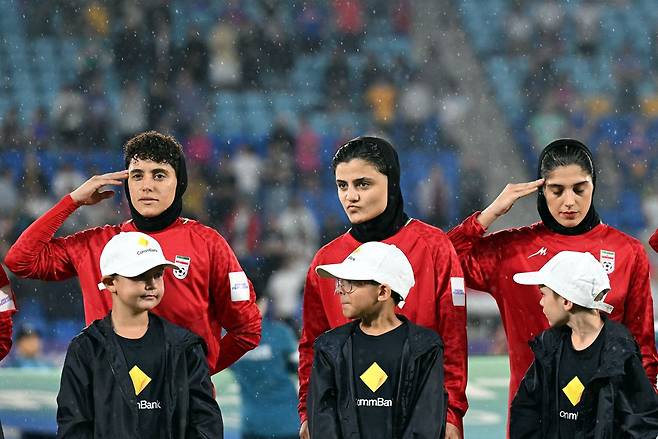 이란 여자 축구 국가대표팀 선수들이 지난 8일(현지시간) 호주 골드코스트 스타디움에서 열린 AFC 여자 아시안컵 A조 필리핀과의 경기 전 국가 연주에 경례하고 있다. 로이터연합