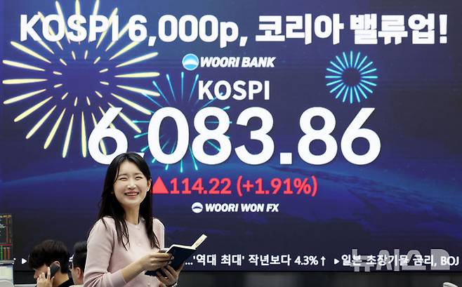 [서울=뉴시스] 김진아 기자 = 코스피가 사상 첫 6000을 돌파한 25일 서울 중구 우리은행 딜링룸에서 직원들이 축하 세리머니를 하고 있다. 2026.02.25. bluesoda@newsis.com