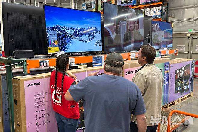 Shoppers consider a large-screen television with the help of a sales associate in a Costco warehouse Thursday, May 1, 2025, in Sheridan, Colo. (AP Photo/David Zalubowski)