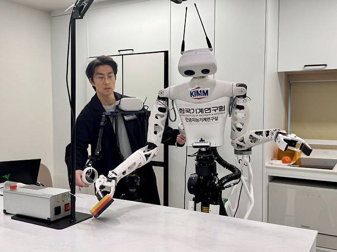 고두열 책임연구원이 마스터 장치를 통해 스펀지를 쥐고 닦는 동작을 하자 AI 로봇이 이를 학습해 실행하고 있다.