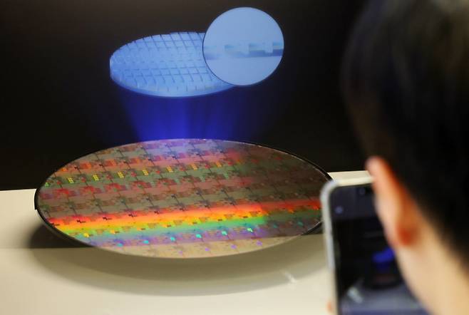 지난달 11일 서울 강남구 코엑스에서 열린 세미콘 코리아 2026를 찾은 한 관람객이 반도체 웨이퍼 사진을 찍고 있다. (자료사진) 2026.02.11 서울=뉴시스