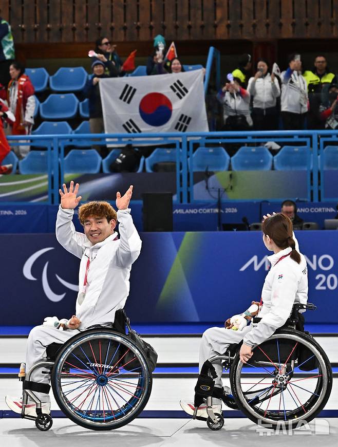 [코르티나담페초=뉴시스] 사진공동취재단 = 휠체어컬링 백혜진(오른쪽)과 이용석이 11일(현지 시간) 이탈리아 코르티나담페초 컬링 올림픽 스타디움에서 열린  2026 밀라노 코르티나 패럴림픽 휠체어컬링 믹스더블에서 은메달을 차지한 뒤 환호하는 관중들에게 인사를 하고 있다. 2026.03.12. photo@newsis.com