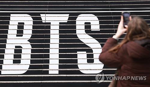 BTS 컴백 공연 알리는 홍보물 (서울=연합뉴스) 진연수 기자 = 11일 서울 종로구 세종문화회관 계단에서 외국인 팬이 '완전체'로 돌아오는 그룹 방탄소년단(BTS) 공연 홍보물을 촬영하고 있다. 2026.3.11 jin90@yna.co.kr