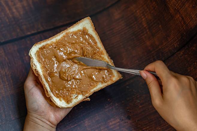 식빵에 땅통버터를 듬뿍 바르고 있다. 주요 견과류 버터 세 가지 가운데 땅콩버터는 단백질, 아몬드버터는 칼슘과 식이섬유, 캐슈버터는 미네랄이 풍부하다. 가끔 입맛과 영양 성분에 따라 골라먹는 재미를 느껴보는 것도 좋다. 사진=게티이미지뱅크