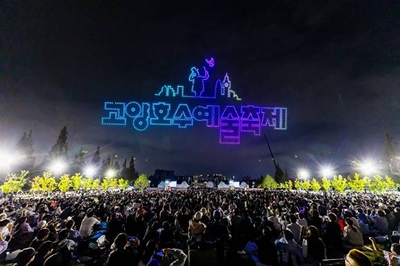 고양호수예술축제에서 화려한 드론 쇼가 밤하늘을 수놓고 있는 가운데 수많은 시민이 잔디밭에 앉아 공연을 관람하고 있다. [사진=고양문화재단]