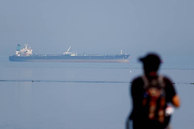 A tourist watches the MT Desert Kite oil tanker carrying Russian oil at Narara Marine National Park in the Arabian Sea, Gujarat, India, on March 11. [REUTERS/YONHAP]