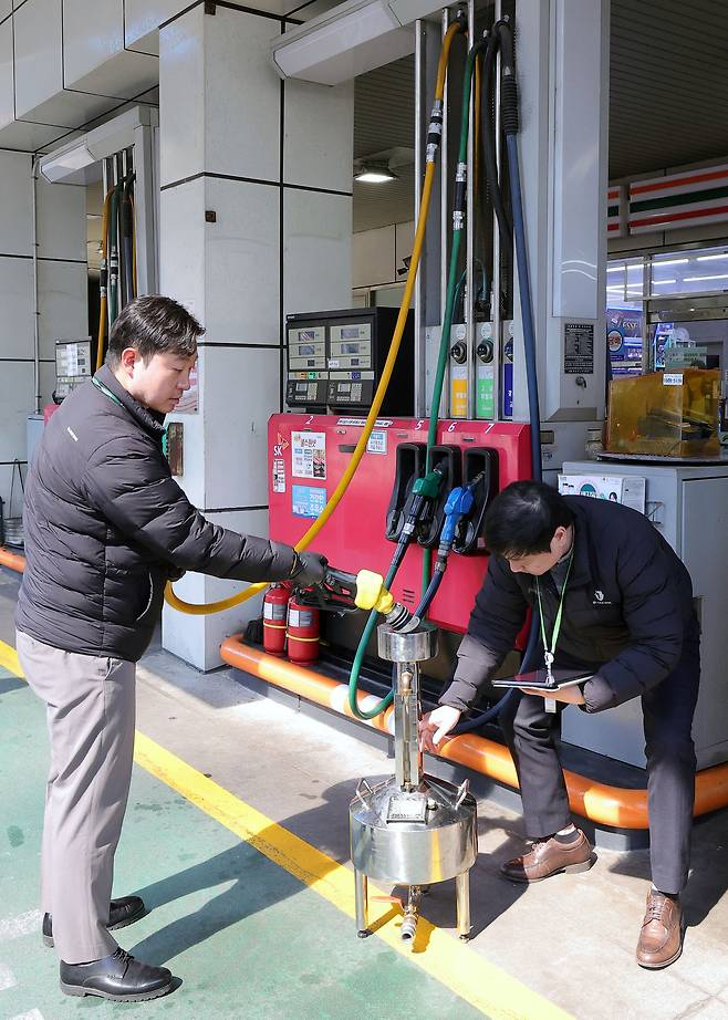 석유 최고가격제 시행 첫날인 13일 서울 마포구 한 주유소에서 한국석유관리원 관계자들이 정량기준탱크를 통해 휘발유 정량 확인을 하고 있다.