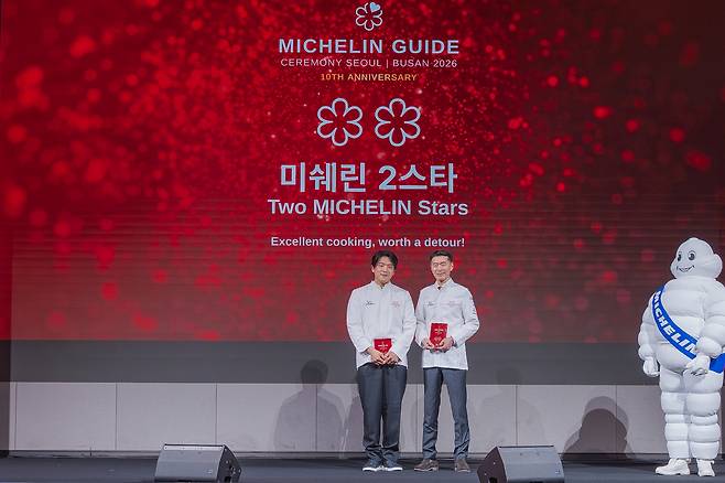 Chef Ahn Sung-jae (left) and chef Park Kyung-jae pose for a photo in Busan, March 5, after the announcement that Mosu and Sosuheon have been awarded two Michelin stars each. (Michelin)