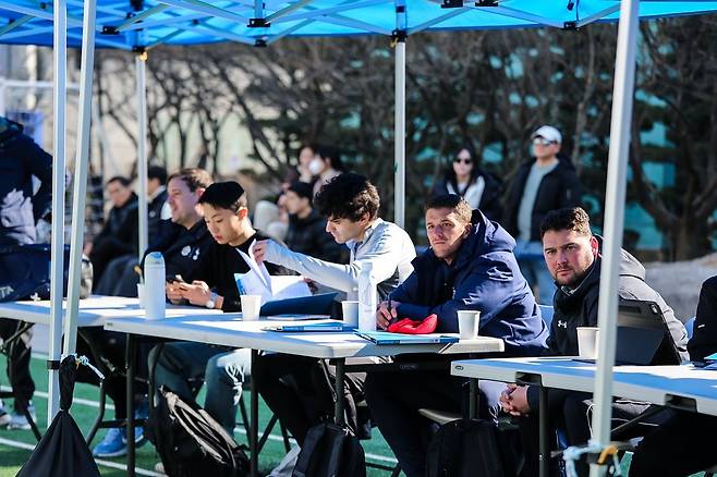 쇼케이스에 초청된 미국 대학 감독 및 코치진이 진지한 표정으로 참가 선수들의 기량을 점검하며 평가 항목을 기록하고 있다.