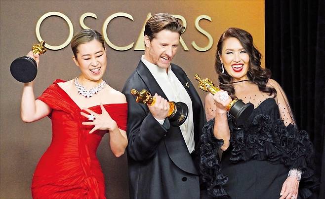 영화 ‘케이팝 데몬 헌터스’를 공동 연출한 매기 강(왼쪽)과 크리스 애펠한스, 제작자 미셸 웡이 15일(현지시간) 열린 ‘제98회 아카데미 시상식’에서 장편 애니메이션·주제가 부문 2관왕에 오른 뒤 오스카 트로피를 들어 올리고 있다. /AP연합뉴스