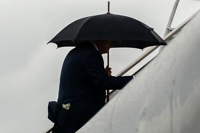 도널드 트럼프 미국 대통령이 15일(현지시간) 플로리다주 팜비치 국제공항에서 에어포스원에 우산을 쓰고 오르고 있다. 연합뉴스