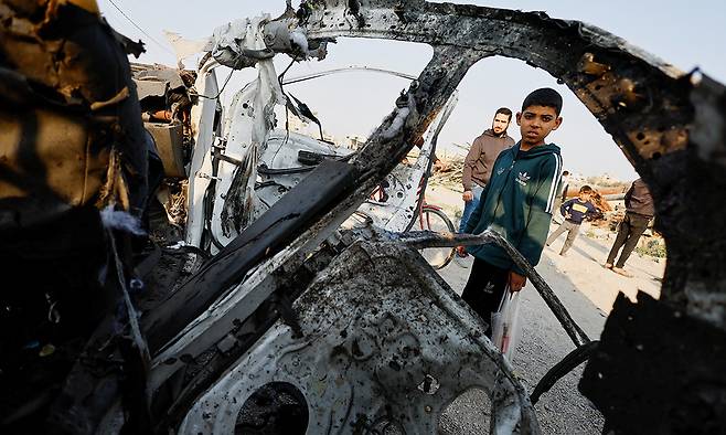 15일(현지시간) 팔레스타인 가자지구에서 한 어린이가 두려운 눈빛으로 이스라엘군의 공습으로 불에 탄 경찰 차량을 바라보고 있다. 팔레스타인 보건 당국은 이스라엘의 가자지구, 서안 공격으로 어린이, 경찰 등 16명이 숨졌다고 밝혔다. 가자=로이터연합뉴스