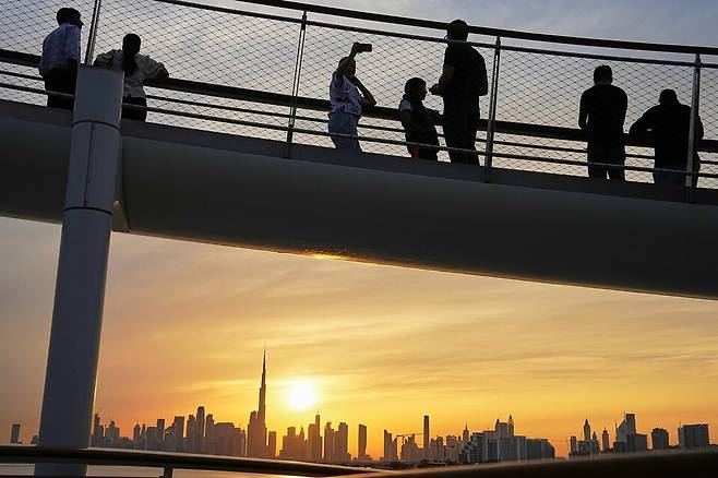 11일 아랍에미리트 두바이의 크릭 하버에서 사람들이 도시 스카이라인과 부르즈 할리가 보이는 가운데 석양을 지켜보고 있다. AP연합뉴스