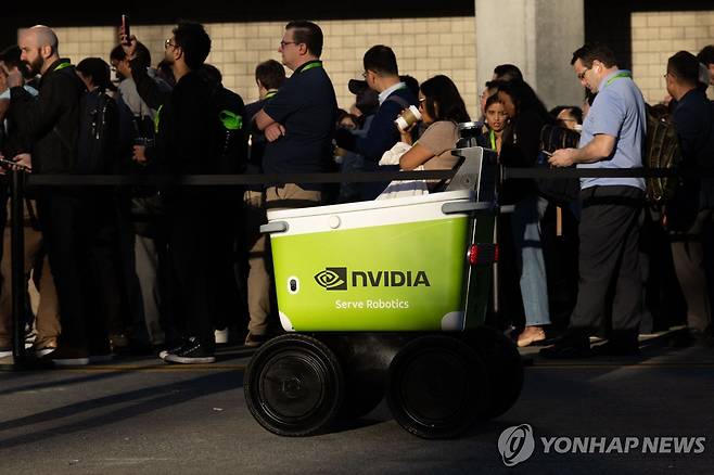 GTC 행사 현장에 늘어선 줄 16일(현지시간) 엔비디아의 연례 개발자대회 'GTC 2026'의 기조연설 행사장 입구에 참관객들이 길게 줄을 늘어선 가운데 배달 로봇이 지나가고 있다. [Getty Images via AFP=연합뉴스]