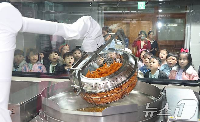 18일 경기 수원시 장안구 대평초등학교 내 위치한 거점형 학교급식 튀김 지원실에서 1학년 학생들이 튀김 조리 로봇이 직접 가동되는 현장을 보고 있다. 2026.3.18 ⓒ 뉴스1 김영운 기자
