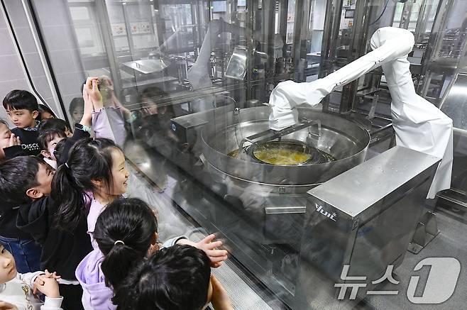 18일 경기 수원시 장안구 대평초등학교 내 위치한 거점형 학교급식 튀김 지원실에서 1학년 학생들이 튀김 조리 로봇이 직접 가동되는 현장을 보고 있다. (공동취재) 2026.3.18 ⓒ 뉴스1 김영운 기자