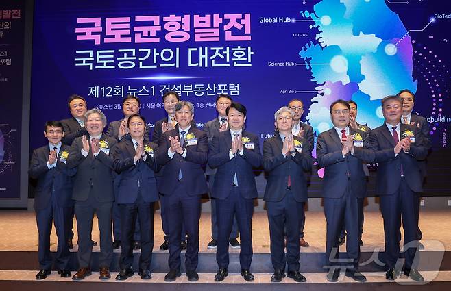 18일 오후 서울 여의도 한국거래소에서 열린 제12회 뉴스1 건설부동산포럼에서 이영섭 대표이사를 비롯한 내빈들이 기념 촬영을 하고 있다. 앞줄 왼쪽부터 김희수 대한건설정책연구원장, 유정훈 대한교통학회장, 강주엽 행정중심복합도시건설청장, 김이탁 국토교통부 제1차관, 국회 국토교통위원회 여당 간사인 복기왕 더불어민주당 의원, 이 대표, 국토위 야당 간사인 이종욱 국민의힘 의원, 김종호 한국공인중개사협회장. 2026.3.18 ⓒ 뉴스1 안은나 기자