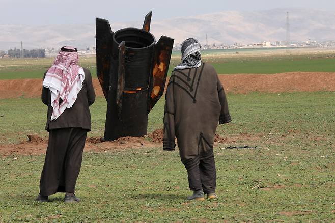 지난 4일 시리아 카미실리 국제공항 인근에 떨어진 미사일 잔해를 지켜보는 사람들. /로이터 연합뉴스