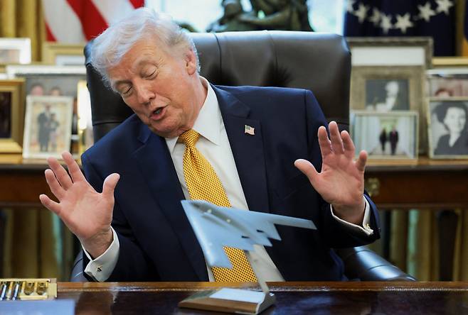 도널드 트럼프 미국 대통령이 16일 백악관 집무실에서 스텔스 폭격기 B-2 모형을 가운데 두고 두 손을 펼쳐 보이고 있다. 트럼프는 이날 ‘미국의 안보 지원’을 언급하며 한국과 일본을 상대로 압박 수위를 높였다./로이터 연합뉴스