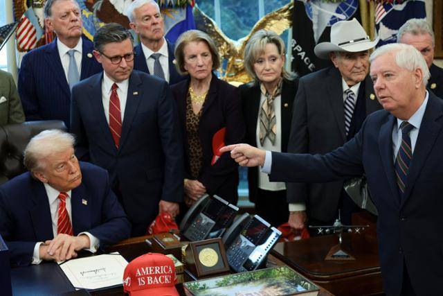 지난달 3일 미국 연방정부 부분 셧다운(예산 공백에 따른 일시 업무 정지) 종료 법안에 서명한 뒤 미 워싱턴 백악관 집무실 책상에 앉아 있는 도널드 트럼프(앞줄 왼쪽) 미 대통령을 그의 측근인 공화당 소속 린지 그레이엄(앞줄 오른쪽) 미 연방 상원의원이 지목하고 있다. 로이터 연합뉴스