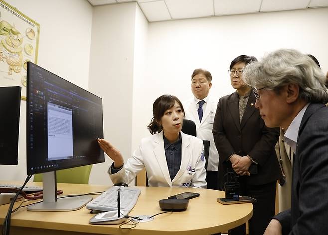 지난 17일 김정은 분당서울대병원 가정의학과 교수가 의료 인공지능(AI)을 활용해 환자 진료를 보고 있다. 뒷 줄에 선 정은경 보건복지부 장관(오른쪽)과 송정한 분당서울대병원장이 진료 중 대화가 모니터에 자동으로 입력되는 것을 보고 있다.  [분당서울대병원]