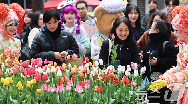 18일 오후 서울 중구 명동거리에서 얄린 '도심에서 미리 만나는 에버랜드 튤립축제' 캠페인에서 에버랜드 공연 연기자들이 시민들에게 싱그러운 튤립 화분을 선물하고 있다. 튤립, 수선화, 무스키리 등 100여 종 120만 송이의 화사한 봄꽃을 선보이는 에버랜드 튤립축제는 오는 20일 막을 올린다. 2026.3.18 ⓒ 뉴스1 오대일 기자