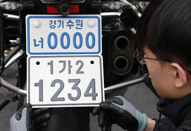 이륜자동차 전국 번호판 제도 시행을 이틀 앞둔 18일 경기 수원시 권선구 수원도시공사 번호판제작소에서 관계자가 번호판 교체 시연을을 하고 있다. 새롭게 도입되는 번호판은 기존 번호판에 표시되던 지역명 표기가 폐지되며 크기가 확대되고 디자인이 변경된다. ⓒ 뉴스1