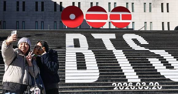 22일 서울 종로구 세종문화회관 계단에서 홍콩에서 온 관광객들이 오는 3월 3년 9개월 만에 '완전체'로 돌아오는 그룹 방탄소년단(BTS)의 컴백을 알리는 홍보물을 기념촬영하고 있다. 2026.1.22 [사진=연합뉴스]