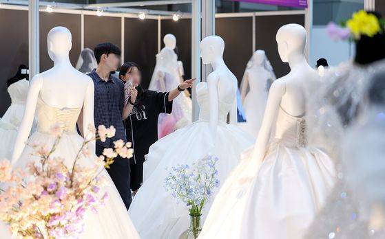 지난해 7월 6일 서울 강남구 삼성동 코엑스에서 열린 2025 추계 웨덱스 웨딩 박람회에서 예비 부부들이 전시된 드레스를 살펴보고 있다. 기사와 직접적 연관 없음. 뉴스1