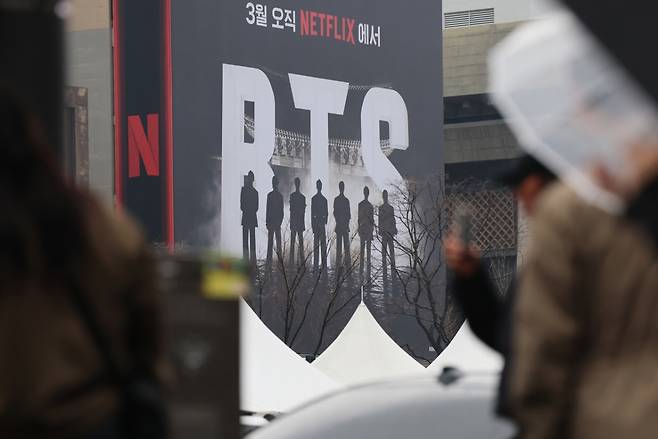 방탄소년단(BTS) 완전체 컴백 공연을 사흘 앞둔 18일 서울 광화문광장에서 외국인 팬들이 컴백 공연을 알리는 전광판 광고를 스마트폰으로 촬영하고 있다./사진=뉴스1.