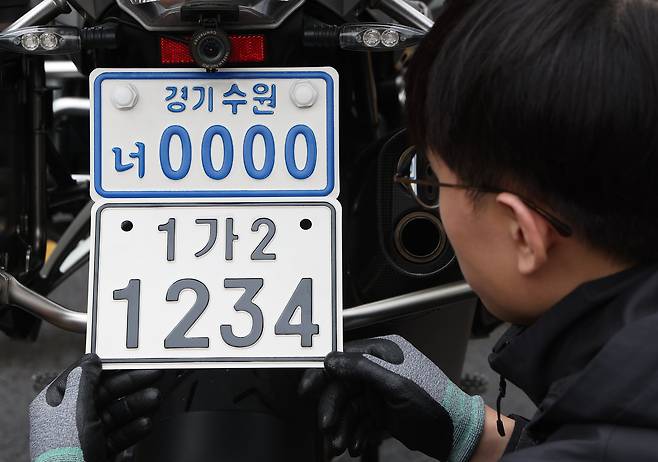 기존 이륜차 번호판(위)과 20일부터 도입되는 새 번호판의 모습. 새 번호판은 세로 길이가 길어지고 지역 명칭이 사라졌으며, 검은색 글자를 적용해 시인성을 높였다. 연합뉴스