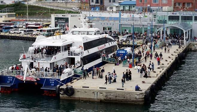 지난해 울릉도 저동항 여객선터미널 부두가 강릉에서 도착한 여객선에서 내린 수많은 관광객으로 북새통을 이루고 있다. 수도권 관광객의 핵심 진입로인 강릉 항로의 운항이 지자체 행정 처분과 선사 간 소송으로 중단되면서, 이 같은 활기찬 모습도 당분간 보기 어려울 전망이다. /경북매일 DB
