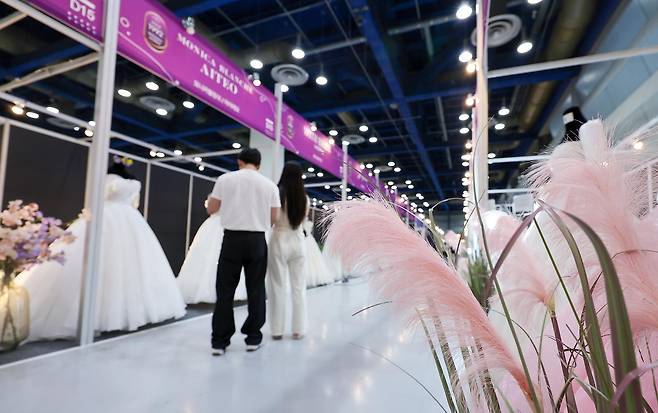 지난해 7월 6일 서울 강남구 삼성동 코엑스에서 열린 2025 추계 웨덱스 웨딩 박람회에서 예비 부부들이 전시된 드레스를 살펴보고 있다. 2025.7.6 뉴스1