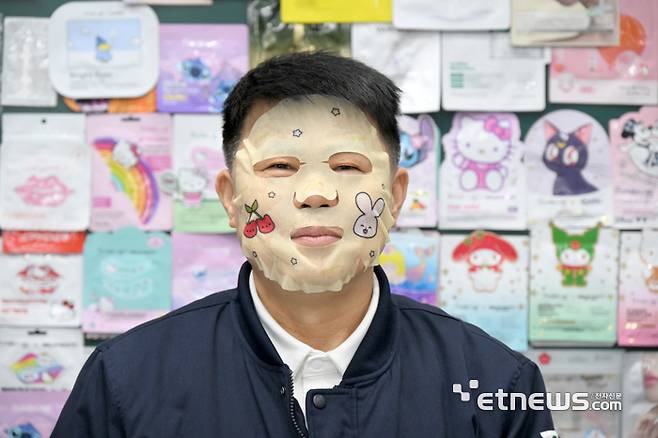 대한민국 K-뷰티 산업을 이끌 김정대 정동산업 대표가 수년동안 개발한 마스크 팩 다지인을 배경으로 자체 개발한 마스크 팩을 쓰고 인터뷰를 하고 있다. 김동욱기자 gphoto@etnews.com